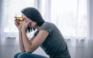 Upset lonely woman with whiskey glass at home